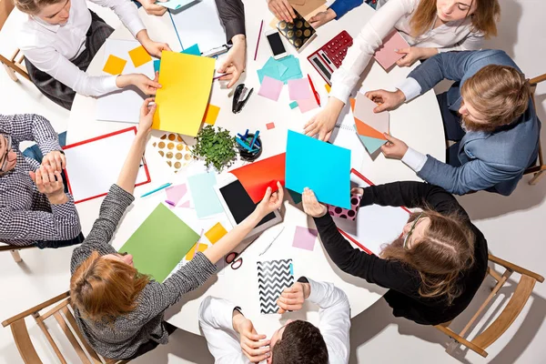 Equipo sentado detrás del escritorio, revisando informes, hablando. Vista superior — Foto de Stock