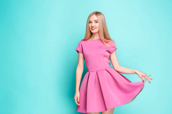 Leende vacker ung kvinna i rosa mini klänning poserar på studio — Stockfoto