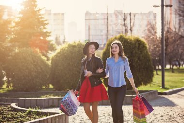 İki kız şehir sokaklarda alışveriş ile yürümek
