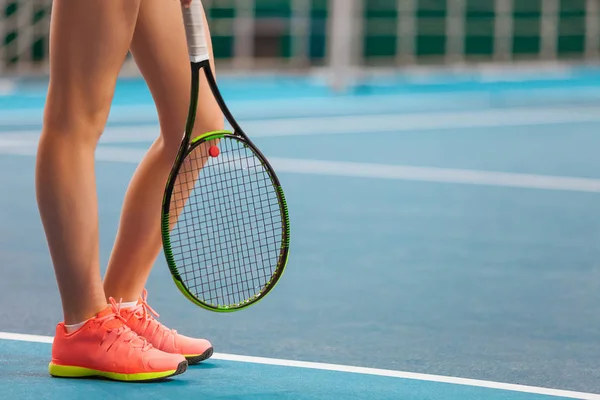 Benen van jong meisje in een gesloten tennisbaan met racket — Stockfoto