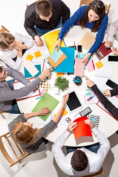 Team sitting behind desk, checking reports, talking. Top View — Stock Photo, Image