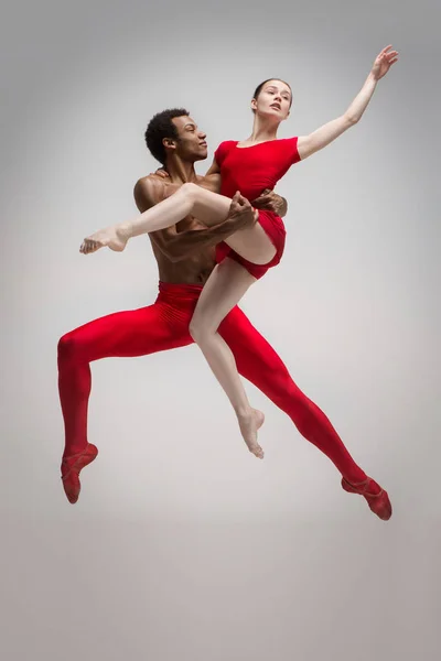 Couple of ballet dancers posing over gray background — Stock Photo, Image