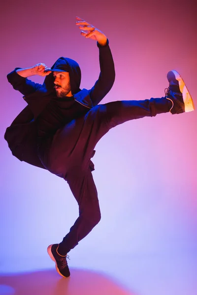 A silhueta de um hip hop dançarino break masculino dançando em fundo colorido — Fotografia de Stock