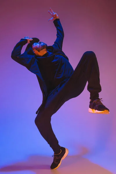 A silhueta de um hip hop dançarino break masculino dançando em fundo colorido — Fotografia de Stock