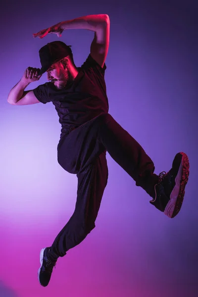Die Silhouette eines männlichen Breakdancers, der auf buntem Hintergrund tanzt — Stockfoto