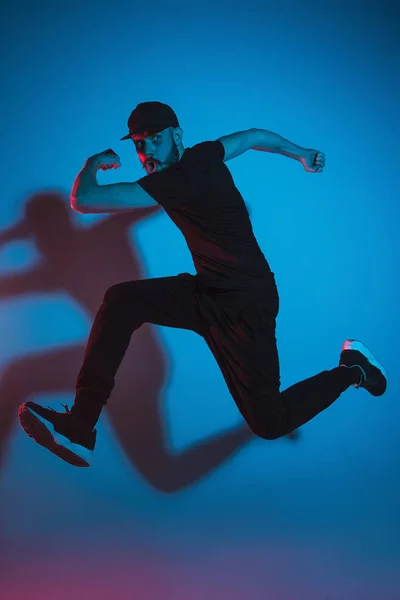 Die Silhouette eines männlichen Breakdancers, der auf buntem Hintergrund tanzt — Stockfoto