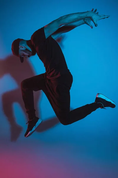 The silhouette of one hip hop male break dancer dancing on colorful background