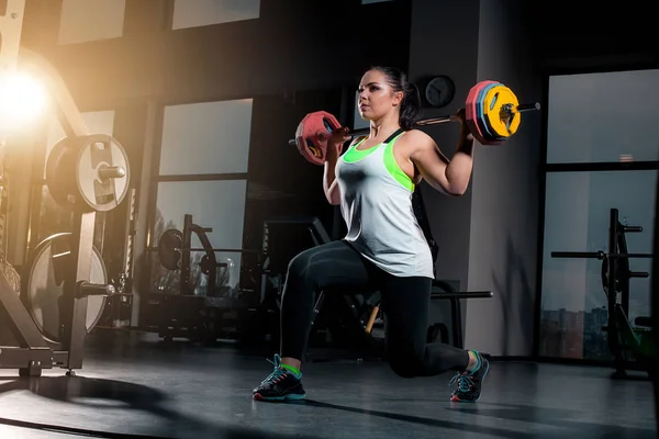 Zinde genç bir kadın ağırlık kaldırıyor odaklanmış görünüyor, spor salonunda çalışıyor. — Stok fotoğraf