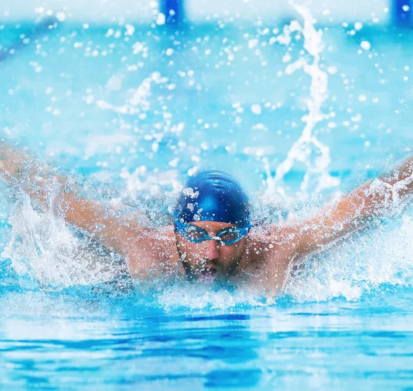 Dynamic and fit swimmer in cap breathing performing the butterfly stroke — Stock Photo, Image