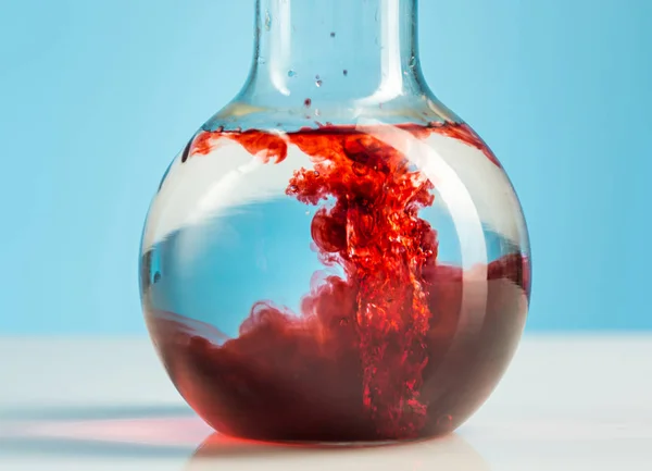 Laborgläser und rote Flüssigkeit innen auf weißem — Stockfoto