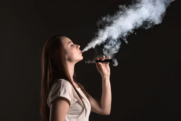 O rosto da jovem vaping no estúdio preto — Fotografia de Stock