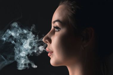 Siyah stüdyo vaping genç kadın yüzü