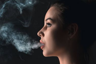 Siyah stüdyo vaping genç kadın yüzü