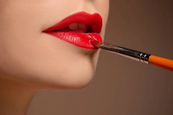 Hermosos labios femeninos con maquillaje y cepillo — Foto de Stock