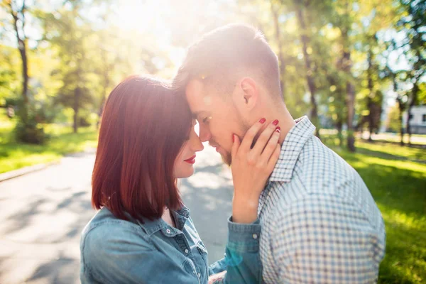 Lyckliga unga paret på park står och skrattar på en solig dag — Stockfoto