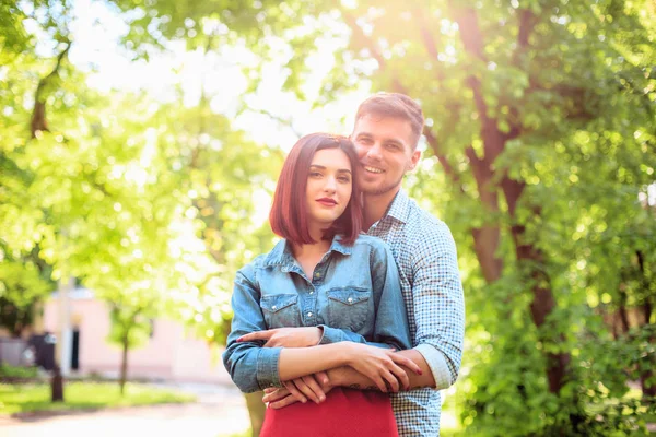 Lyckliga unga paret på park står och skrattar på en solig dag — Stockfoto