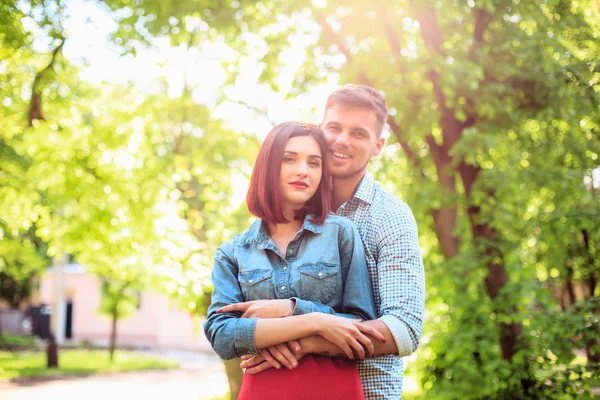 Feliz pareja joven en el parque de pie y riendo en el día soleado brillante —  Fotos de Stock