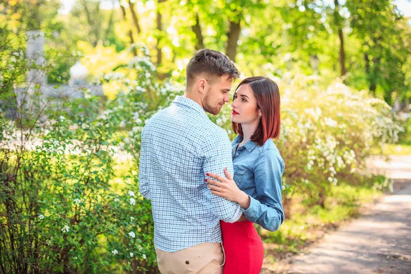 Jovem casal feliz no parque de pé e rindo no dia ensolarado brilhante — Fotografia de Stock