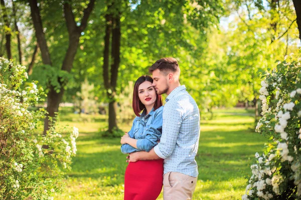 Feliz pareja joven en el parque de pie y riendo en el día soleado brillante — Foto de Stock