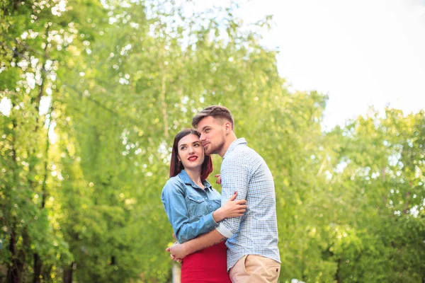 Glückliches junges Paar im Park stehend und lachend an einem strahlend sonnigen Tag — Stockfoto