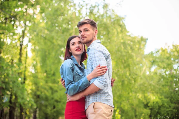 Feliz pareja joven en el parque de pie y riendo en el día soleado brillante —  Fotos de Stock