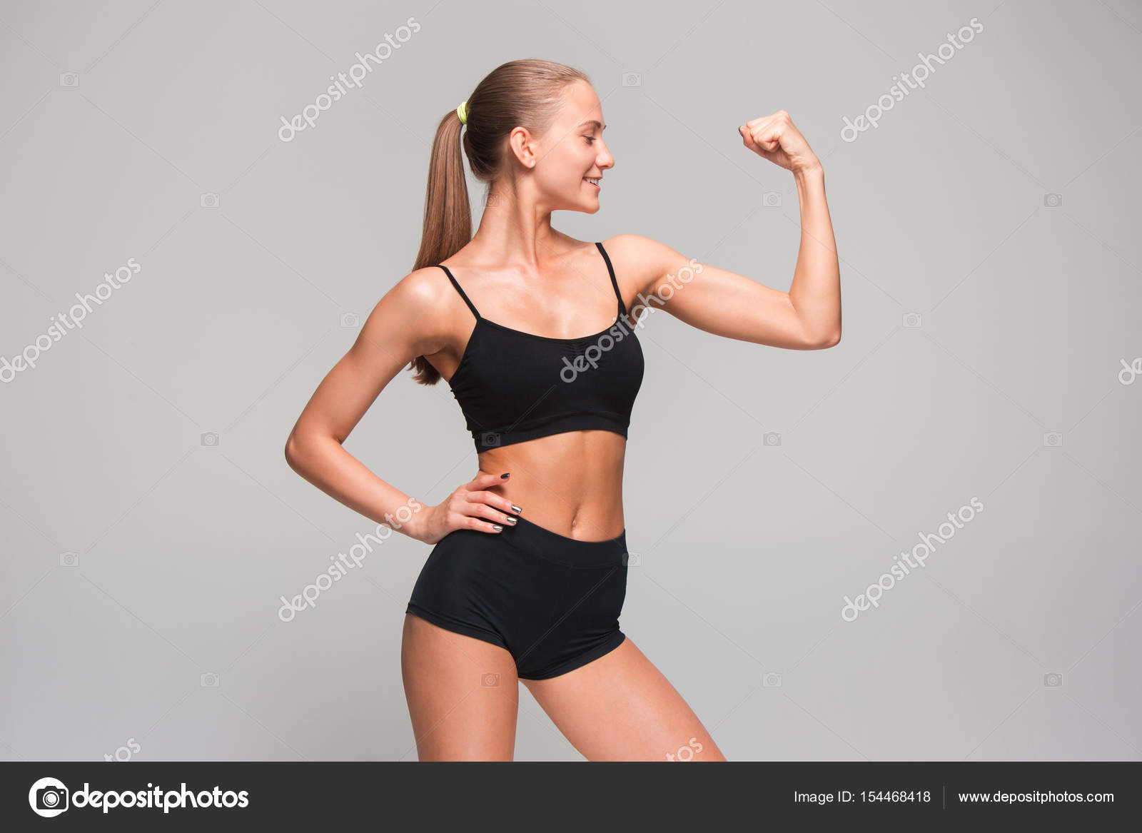 Muscular young woman athlete on gray Stock Photo by ©vova130555