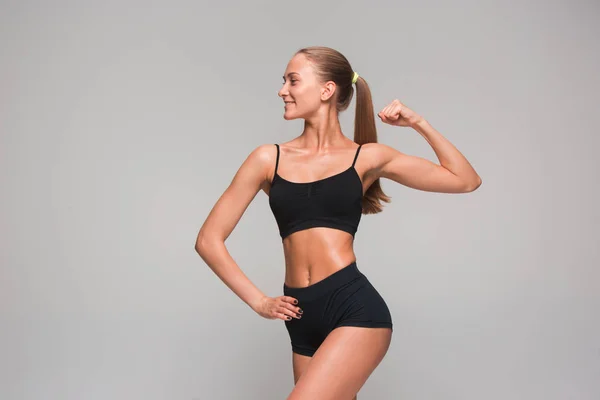 Muskulös ung kvinna idrottsman på grå — Stockfoto