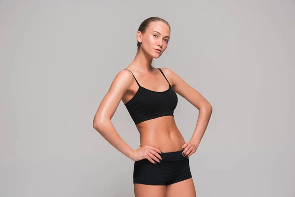 Muscular young woman athlete on gray — Stock Photo, Image