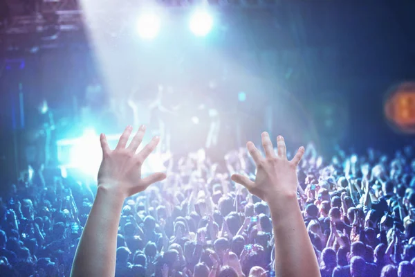 Las siluetas de la multitud de conciertos frente a las luces del escenario brillantes — Foto de Stock