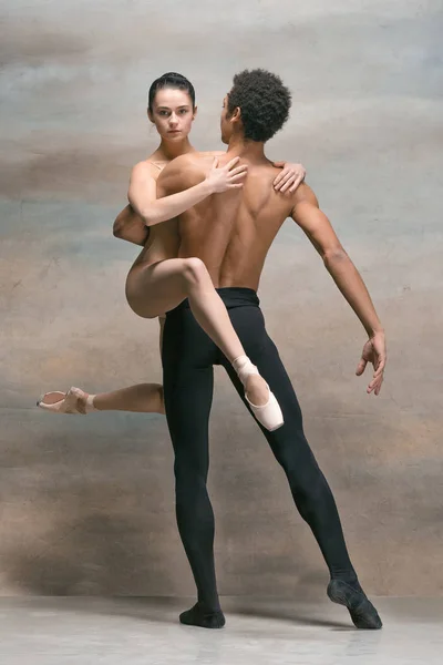 Couple of ballet dancers posing over gray background — Stock Photo, Image