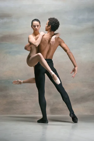 Couple of ballet dancers posing over gray background — Stock Photo, Image