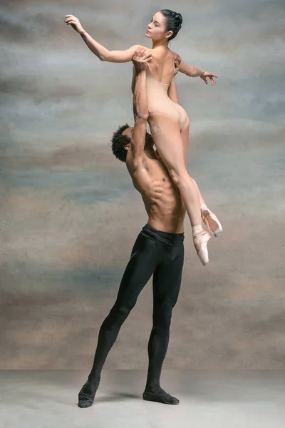 Couple of ballet dancers posing over gray background — Stock Photo, Image