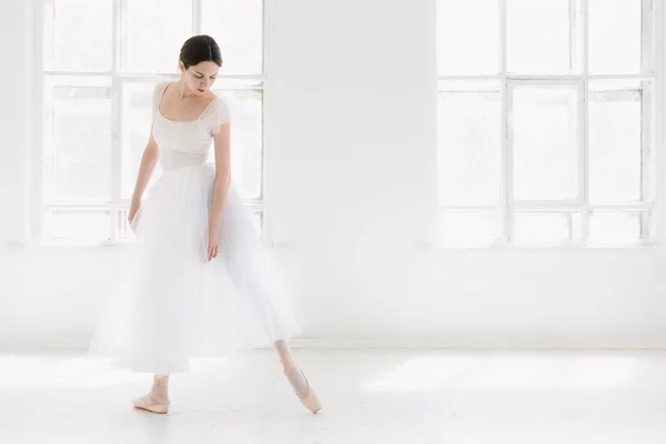 Jovem e incrivelmente bela bailarina está posando e dançando em um estúdio branco — Fotografia de Stock