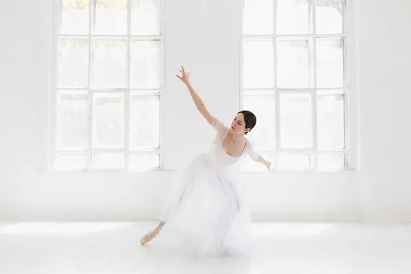 Молодая и невероятно красивая балерина позирует и танцует в белой студии — стоковое фото