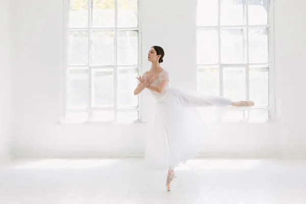 Jonge en ongelooflijk mooie ballerina is poseren en dansen in een witte studio — Stockfoto