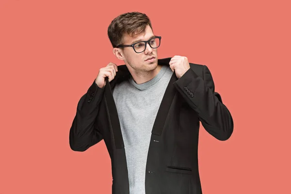 Joven hombre guapo en traje negro y gafas aisladas sobre fondo rojo — Foto de Stock