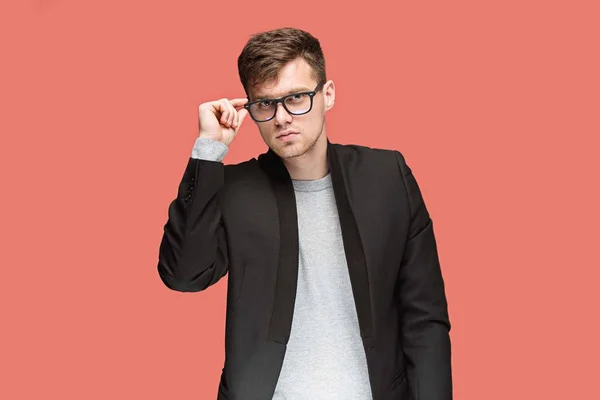 Jovem homem bonito em terno preto e óculos isolados no fundo vermelho — Fotografia de Stock