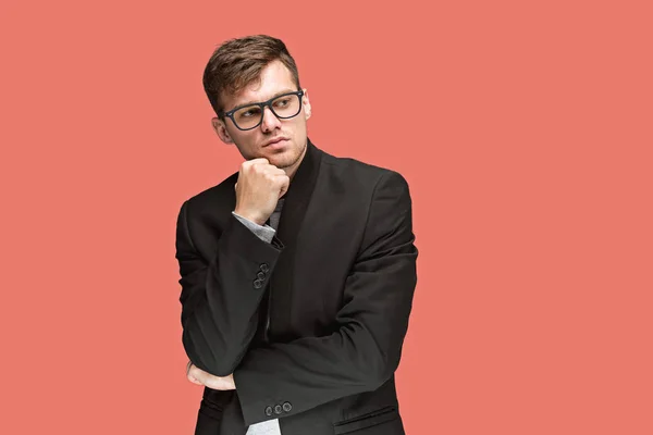 Joven hombre guapo en traje negro y gafas aisladas sobre fondo rojo — Foto de Stock