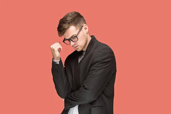 Joven hombre guapo en traje negro y gafas aisladas sobre fondo rojo — Foto de Stock