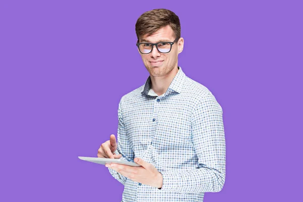 O jovem em uma camisa que trabalha no computador portátil no contexto lilás — Fotografia de Stock