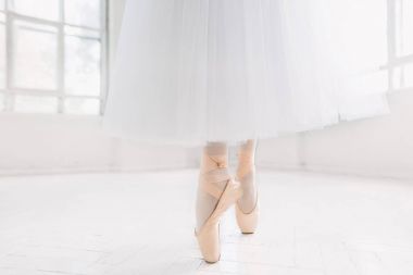 Genç balerin, closeup bacaklar ve ayakkabı, pointe pozisyonda ayakta.