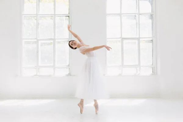 Молодая и невероятно красивая балерина позирует и танцует в белой студии — стоковое фото