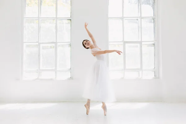 Jonge en ongelooflijk mooie ballerina is poseren en dansen in een witte studio — Stockfoto