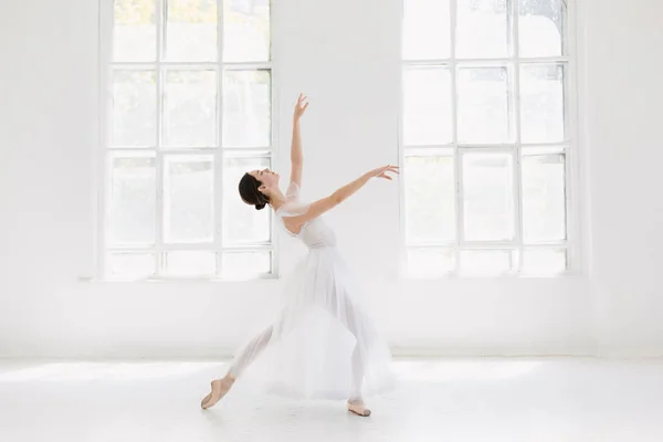 Jovem e incrivelmente bela bailarina está posando e dançando em um estúdio branco — Fotografia de Stock