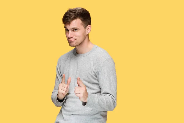 The young man smiling and looking and pointing at cameraaway — Stock Photo, Image