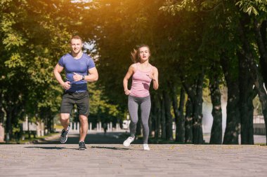 Sportif kadın ve adam gündoğumu ışık Park'ta jogging