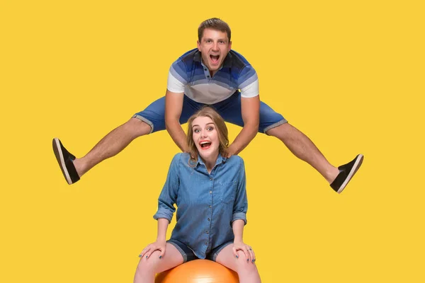 Portrait of a young couple jumping against yellow background — Stock Photo, Image