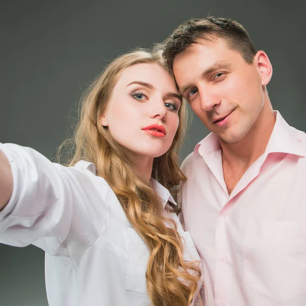 Retrato de una joven pareja de pie sobre fondo gris — Foto de Stock