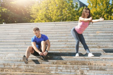 Uygun Fitness kadın ve adam açık havada Park'ta germe egzersizleri yapıyor