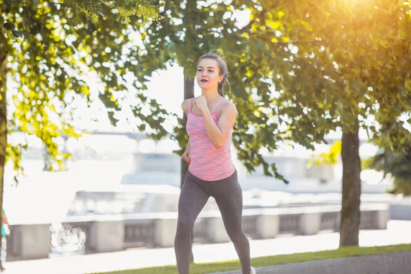 Temmelig sporty kvinde jogging på park i solopgang lys - Stock-foto